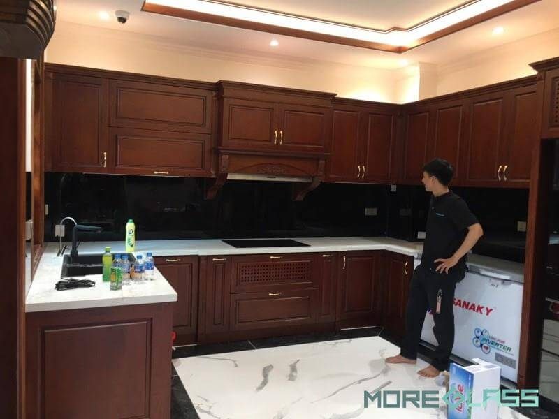 Thi công phòng bếp với mẫu thiết kế tủ bếp chữ U phong cách tân cổ điển, mặt bàn bếp ốp đá nhân tạo cao cấp, kính cường lực ốp bếp màu đen bí ẩn, mang đến cho không gian phòng bếp của bạn vẻ đẹp tinh tế, sang trọng dành cho chung cư, nhà phố, biệt thự